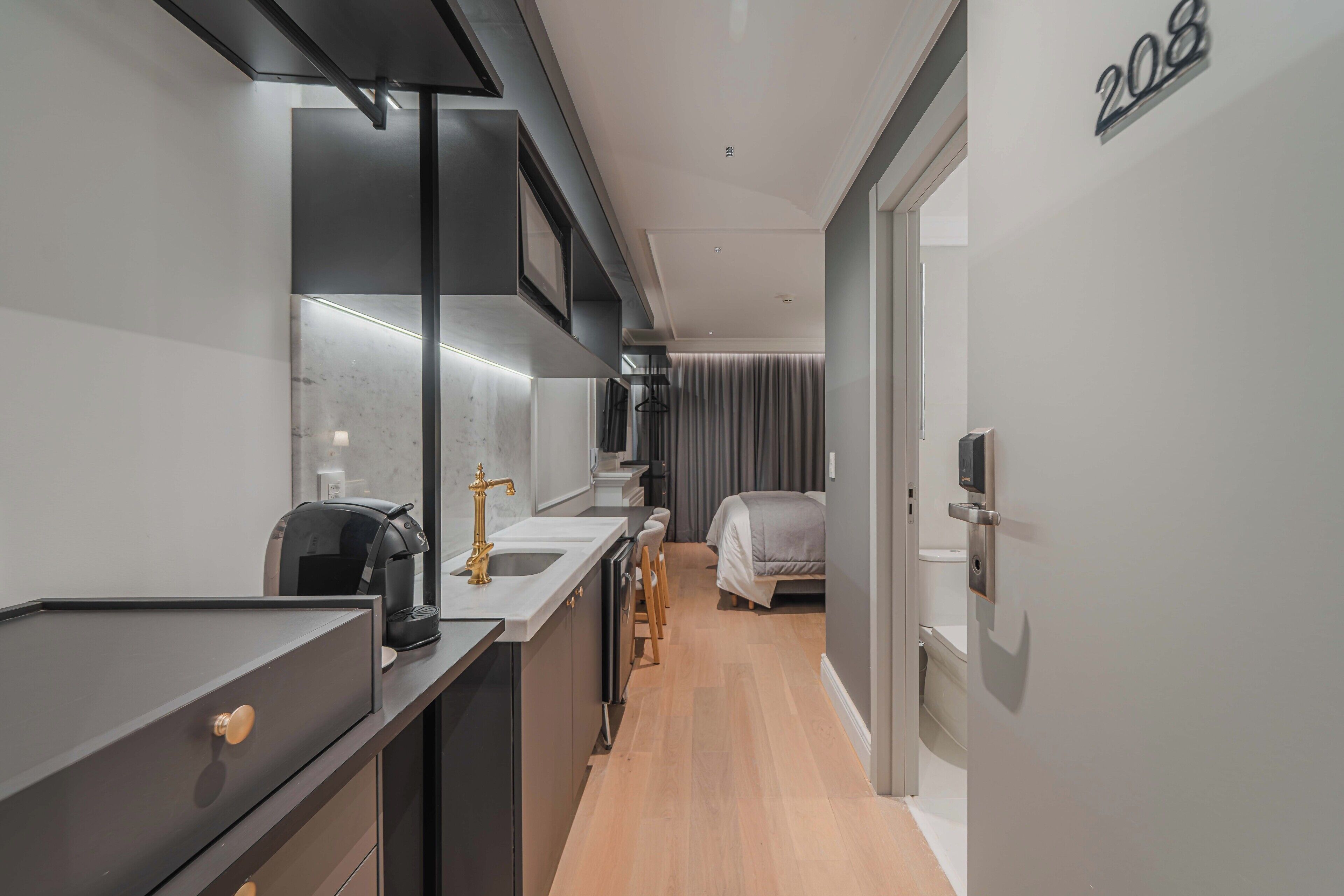 Una habitación de hotel moderna con kitchenette, una cama y un baño.