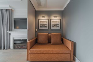 A modern living room with a sofa, fireplace, and two framed artworks on the wall.