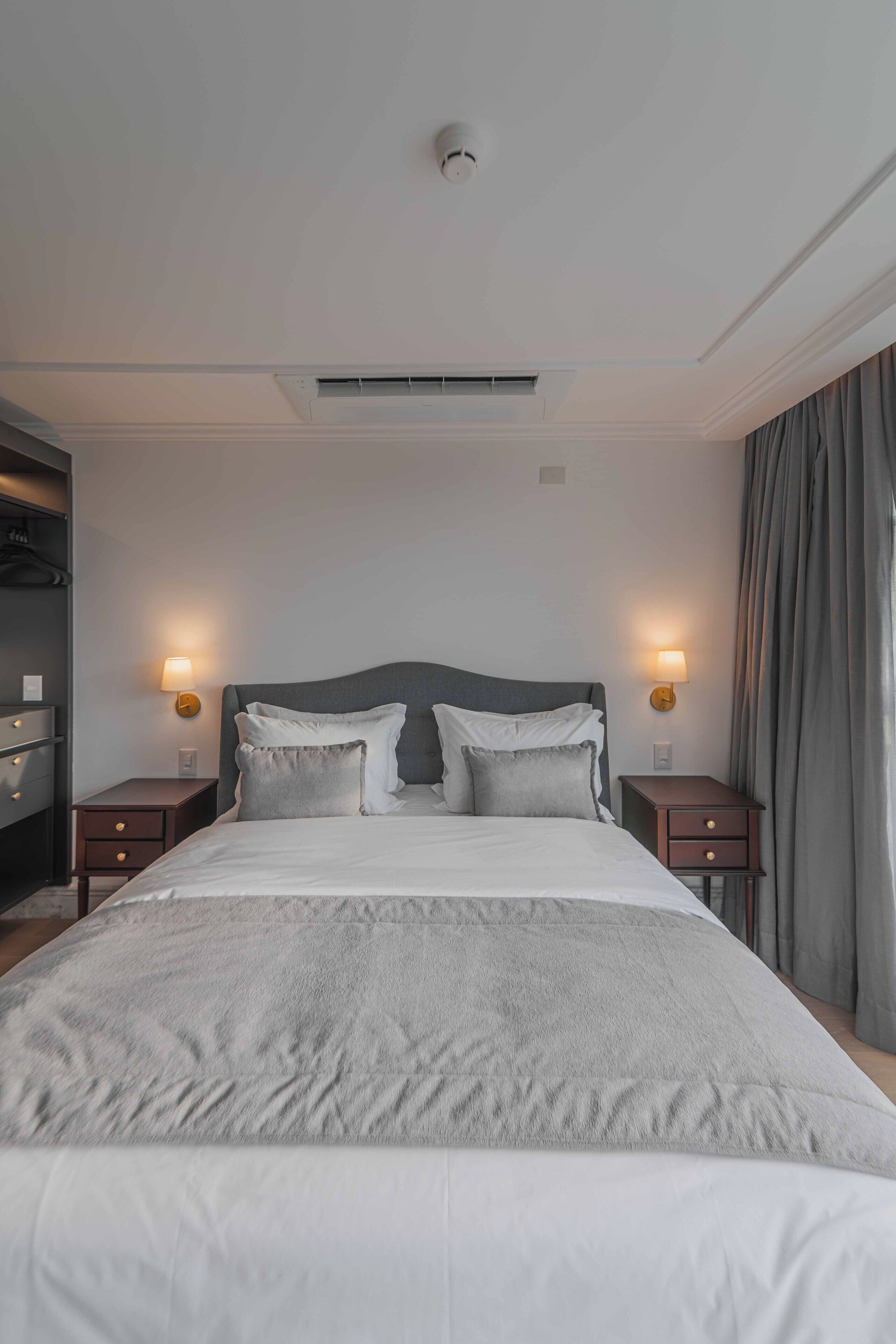 Ein Hotelzimmer mit einem großen Bett, zwei Nachttischen, einer Wandleuchte und einem Deckenventil.