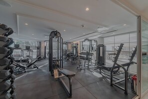 A gym with various exercise equipment, large windows, and a clean, modern design.