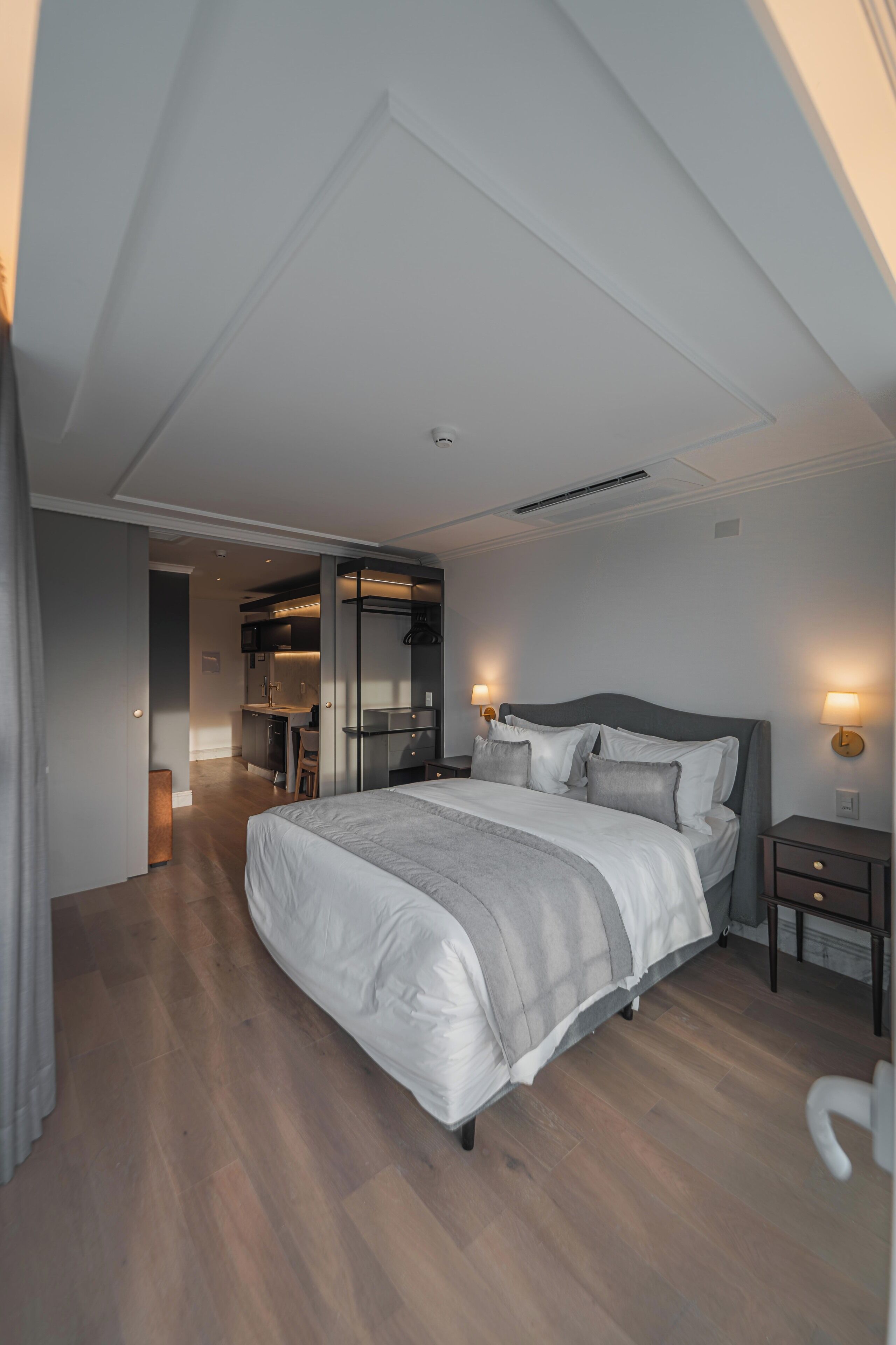 Ein modernes Schlafzimmer mit einem großen Bett, Nachttischen, einem Kleiderschrank und einem durch eine offene Tür einsehbaren Badezimmer.