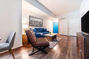 A modern living room with a sofa, armchair, coffee table, and a television. - Landing | Spectacular 1BD, Gym, Yoga Studio (Omaha)
