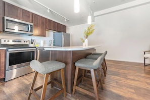 Eine moderne Küche mit Edelstahlgeräten, Holzschränken und einer Bar mit Sitzgelegenheiten.