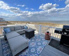 A deck with a gray sofa, a small table, and a grill. - 3-bedroom house on charming Broadkill Beach with AC for cool, relaxing stays (Milton)