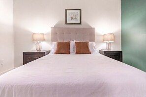 A hotel room with a large bed, two bedside tables, and a framed picture on the wall. - Landing | Amazing 1BD, Yoga Studio, Gym (Omaha)