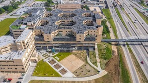 A multi-story building with a flat roof, surrounded by parking areas and a highway. - Landing | Stunning 1BD, Gym, Yoga Studio (Omaha)