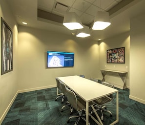 A conference room with a long table, chairs, a flat-screen TV, and artwork on the walls. - Landing | Modern 1BD, Yoga Studio, Gym (Omaha)