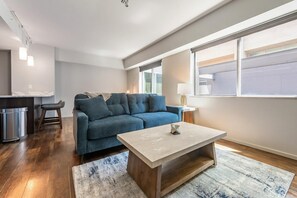 Ein modernes Wohnzimmer mit einer Couch, einem Couchtisch und einem Fenster mit Jalousien.
