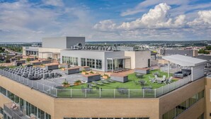 Een dakterras met terrasmeubilair, een modern gebouw en een heldere lucht.