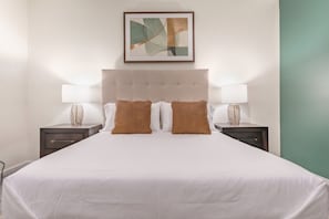 A hotel room with a large bed, two nightstands, a framed abstract artwork, and a green accent wall. - Landing | Incredible 2BD, Gym, Yoga Studio (Omaha)