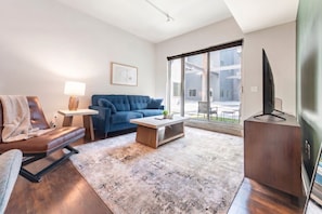 A modern living room with a sofa, coffee table, and a flat-screen TV. - Landing | Incredible 2BD, Gym, Yoga Studio (Omaha)