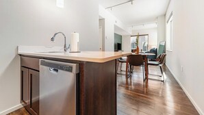 Eine moderne Küche mit Geschirrspüler, einer Holztischinsel und einem Essbereich mit Stühlen.