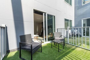 Ein Balkon mit zwei Stühlen, einem Tisch und einer Schiebeglastür, mit Blick ins Innere.