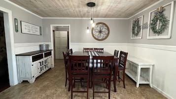 Un comedor con una mesa y sillas de madera, un adorno en la pared y un armario blanco.