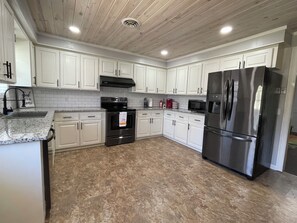 A kitchen with white cabinets, a stainless steel refrigerator, a stove, and a microwave. - Spacious 4-bedroom home near the park & downtown charming Iuka (Iuka)