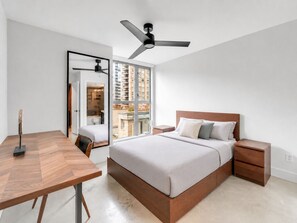 Ein modernes Schlafzimmer mit Bett, Nachttischen, Schreibtisch und Deckenventilator.