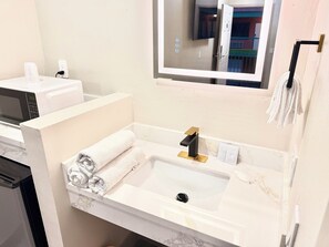 Un baño con un lavamanos blanco, un grifo negro y un espejo encima.