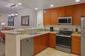 A modern kitchen with granite countertops, stainless steel appliances, wooden cabinets, and a built-in dishwasher. - Luxury Orlando Christmas getaway at Marriott Vacation Club near Disney! (Orlando)