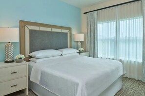 A hotel room with a bed, a nightstand, a lamp, and a window with curtains. - Luxury Orlando Christmas getaway at Marriott Vacation Club near Disney! (Orlando)