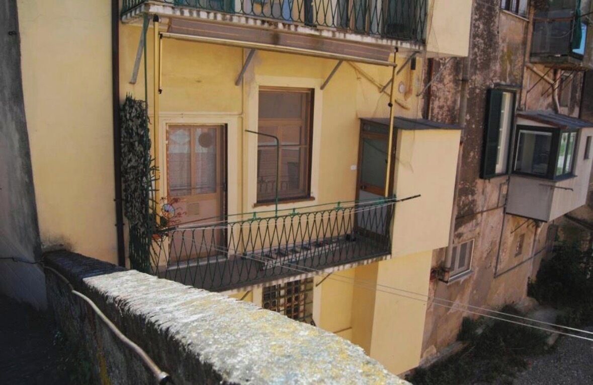 Un immeuble à plusieurs étages, doté de balcons, d’une porte bien visible et d’une fenêtre.