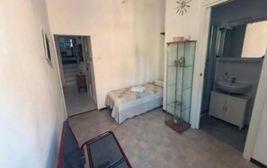 A bedroom with a bed, a glass cabinet, and a bathroom with a sink and cabinet. - At Cà du Grillu (Albisola Superiore)
