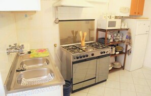 A compact kitchen with a gas stove, sink, and a microwave. - At Cà du Grillu (Albisola Superiore)