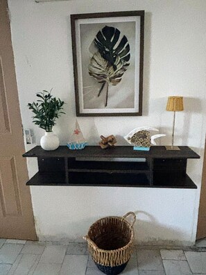 A wall-mounted shelf with a framed leaf artwork, a potted plant, decorative items, and a lamp. - 2-bedroom apartment in welcoming Mazatlán with AC for comfort (Mazatlán)