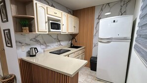 A compact kitchen with a microwave, a refrigerator, a sink, and a wooden island. - 2-bedroom apartment in welcoming Mazatlán with AC for comfort (Mazatlán)