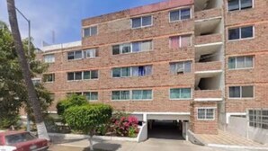 A multi-story brick building with a parking area in front. - 2-bedroom apartment in welcoming Mazatlán with AC for comfort (Mazatlán)