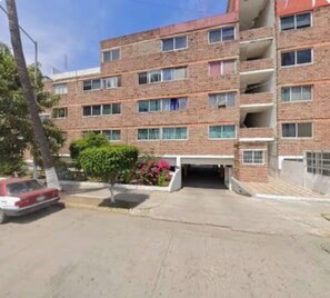 A multi-story brick building with a parking area in front. - 2-bedroom apartment in welcoming Mazatlán with AC for comfort (Mazatlán)