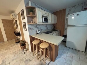 A kitchen with a marble backsplash, white cabinets, a built-in microwave, and a refrigerator. - 2-bedroom apartment in welcoming Mazatlán with AC for comfort (Mazatlán)