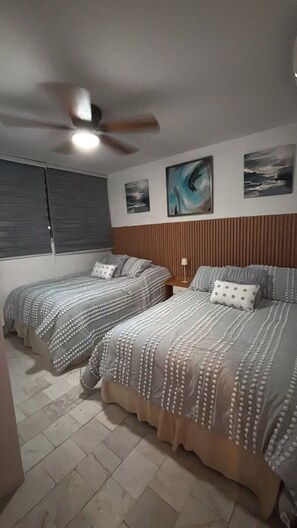 A bedroom with two beds, a ceiling fan, and artwork on the wall. - 2-bedroom apartment in welcoming Mazatlán with AC for comfort (Mazatlán)