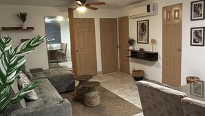 A spacious living area with a grey sofa, a dining table, and a ceiling fan. - 2-bedroom apartment in welcoming Mazatlán with AC for comfort (Mazatlán)