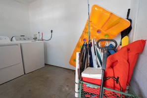 Ein Waschraum mit Waschmaschine, Trockner und einem Metallgestell für Reinigungsmittel.