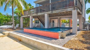 A two-story building with a pool, a balcony, and a staircase leading to the upper level. - Pet-Friendly Boater’s Retreat- Pool, Dock & Kayaks (Marathon)