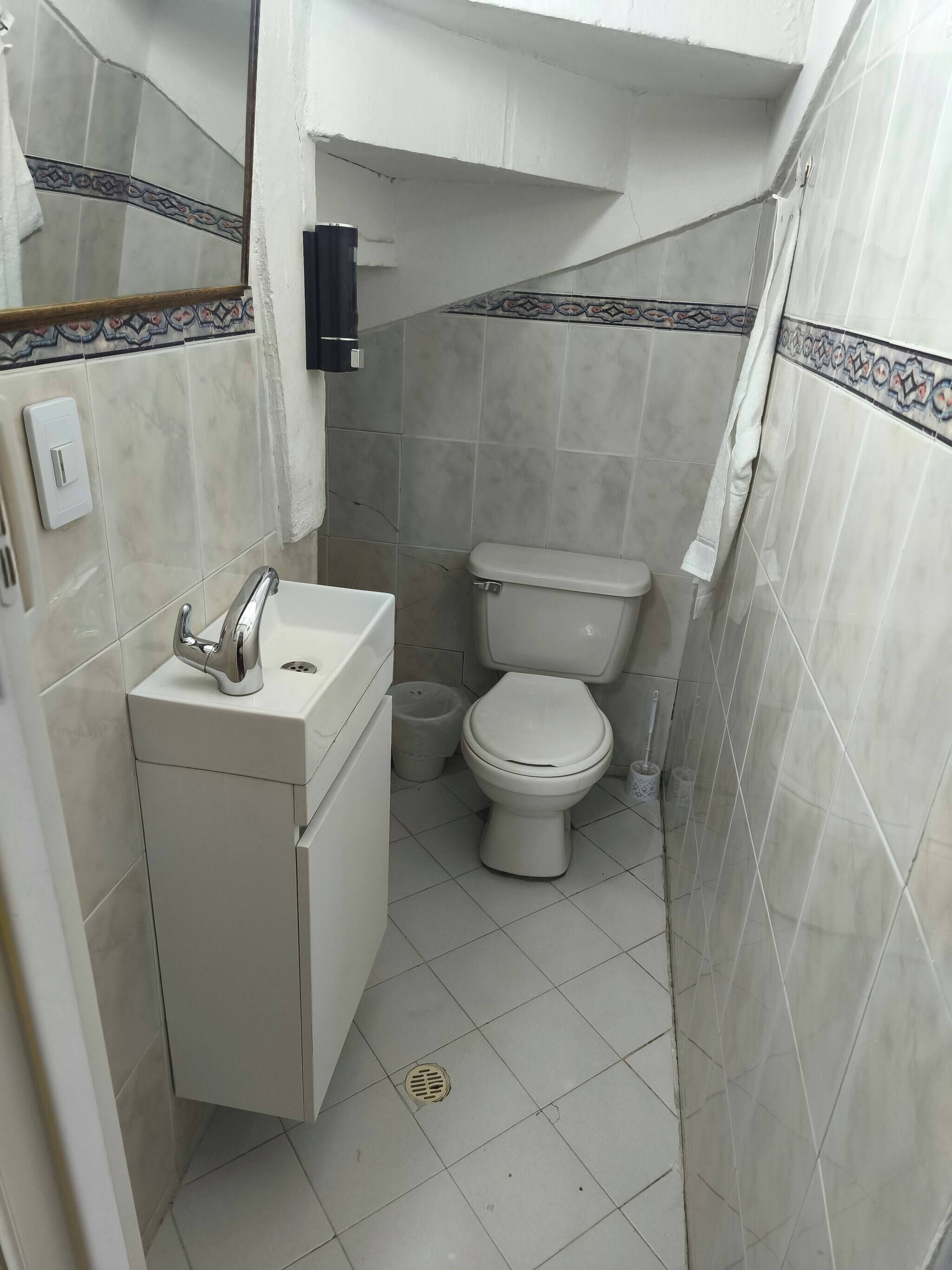 Een kleine badkamer met toilet, wastafel en een vuilnisbakje.