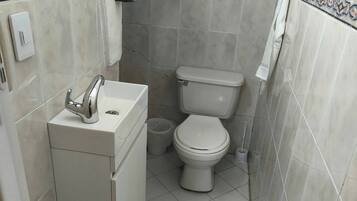 Un baño pequeño con inodoro, lavamanos y un cesto de basura.