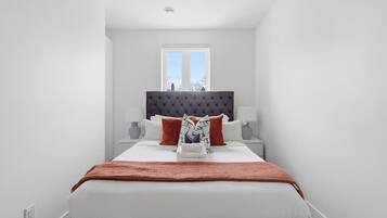 A bedroom with a large bed, a window, and a view of the outside.