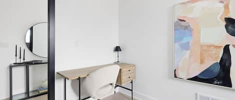 Un espace de bureau moderne comprenant un bureau, une chaise et un grand tableau abstrait accroché au mur.