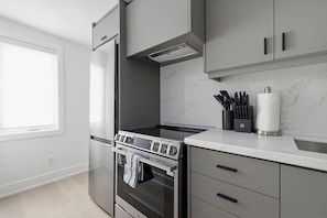 Eine moderne Küche mit Einbauofen, Kochfeld und Edelstahl-Kühlschrank.