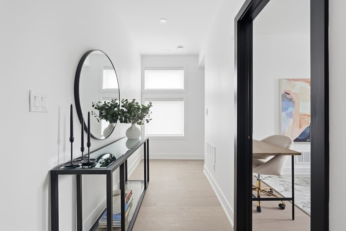 A hallway with a console table, a mirror, and a potted plant.