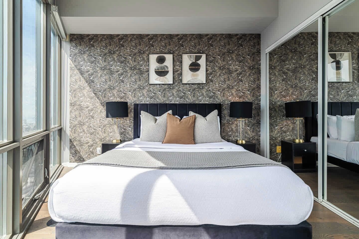 Une chambre moderne avec un grand lit, deux lampes de chevet et une vue sur la ville.