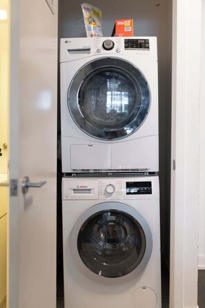 A stacked washer and dryer unit with a Bosch label, a digital display, and a sensor dry feature. - Stylish 2BR City Retreat Near the Lake & Park (Toronto)