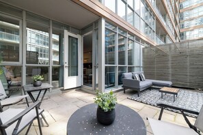 An outdoor patio with a sofa, chairs, and a table. - Stylish 2BR City Retreat Near the Lake & Park (Toronto)