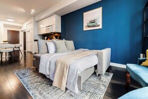 A modern bedroom with a bed, a dining area, and a kitchen. - Stylish 2BR City Retreat Near the Lake & Park (Toronto)