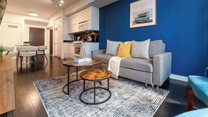 Ein modernes Wohnzimmer mit grauem Sofa, Couchtisch und Wand in Blautönen.