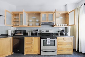 Eine moderne Küche mit Holzschränken, einer Mikrowelle, einem Backofen und einem Geschirrspüler.