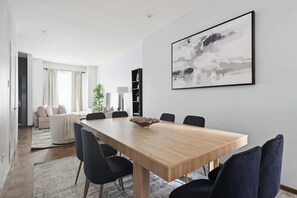 A modern dining area with a wooden table, black chairs, and a large abstract painting on the wall. - Grand 4BR Downtown Townhome escapade (Toronto)