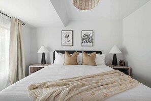 A hotel room with a bed, two nightstands, a lamp, a framed artwork, and a window with curtains. - Grand 4BR Downtown Townhome escapade (Toronto)