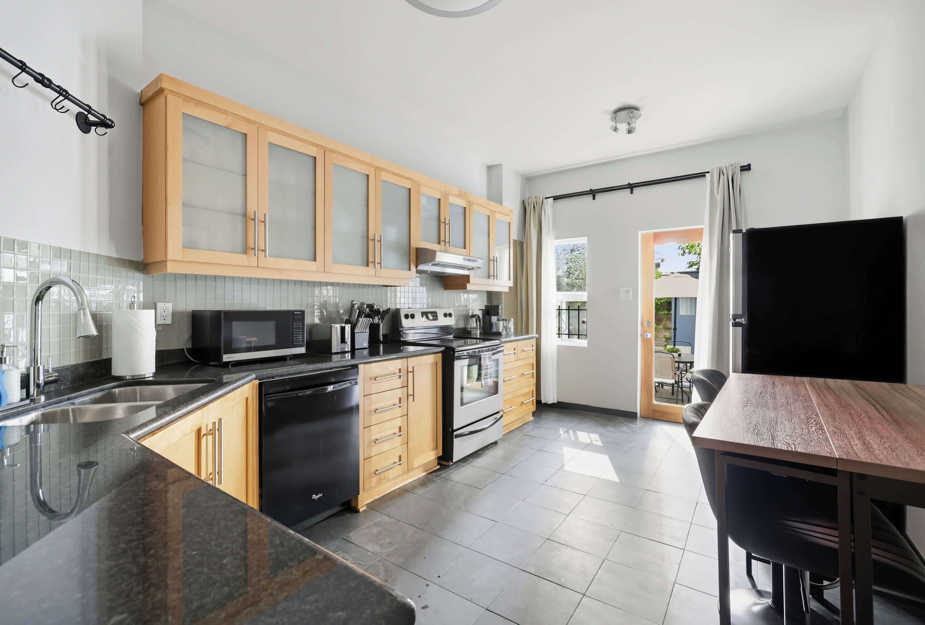 A modern kitchen with wooden cabinets, a microwave, stove, and a dining area with a table and chairs.